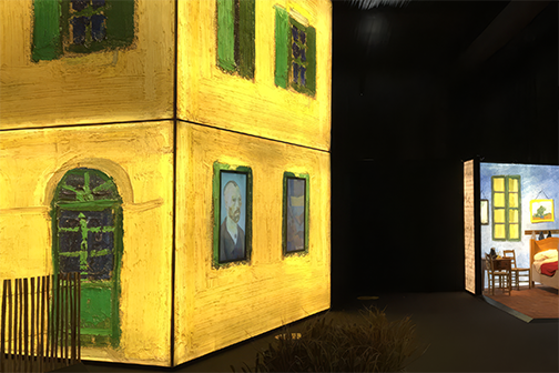 Immersive Van Gogh exhibition installation recreating the Yellow House facade in 3D, with a glimpse of the painted bedroom scene in the background.