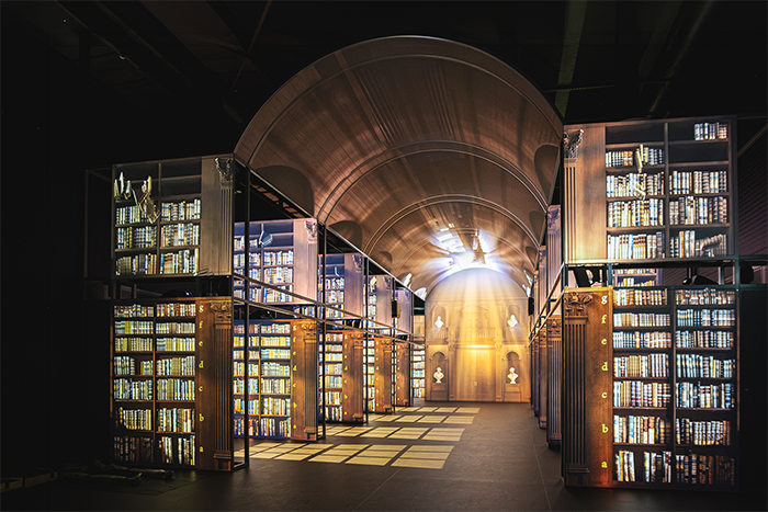 Recreated Long Room library interior at the Book of Kells experience, with illuminated bookshelves lining a vaulted corridor receding into the distance.